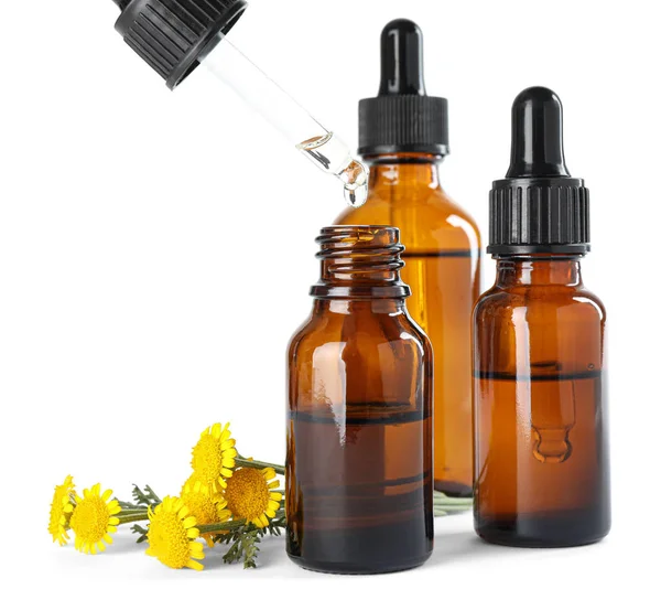 Drop pflanzliches ätherisches Öl in Flasche und Blüten isoliert auf weiß — Stockfoto