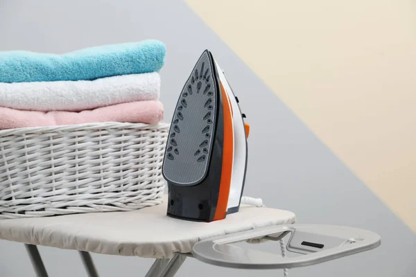Ny modern järn och korg med tvätt ombord mot färg bakgrund — Stockfoto