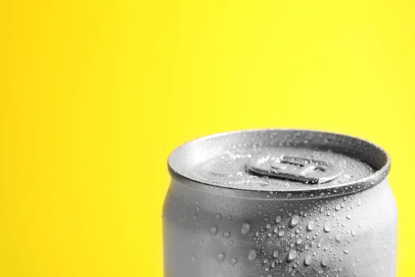 Aluminum can of beverage covered with water drops on yellow background, closeup. Space for text — Stock Photo, Image