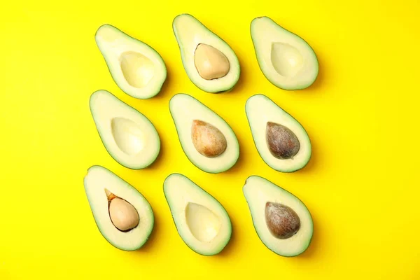 Snijd verse rijpe avocado's op gele achtergrond, platte lay — Stockfoto