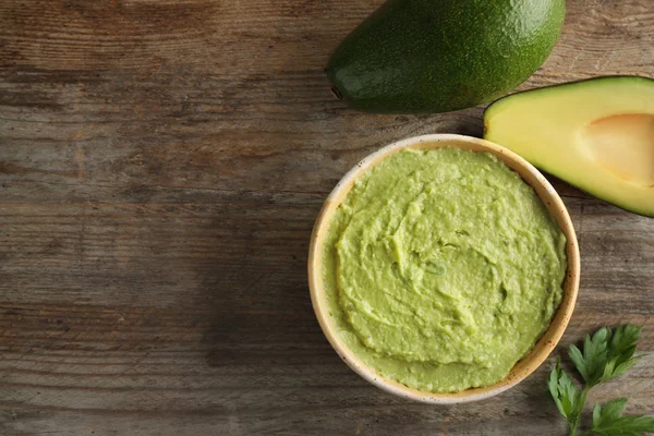 Composizione posata piatta con ciotola di guacamole fatta di avocado maturi su tavolo di legno marrone. Spazio per testo — Foto Stock