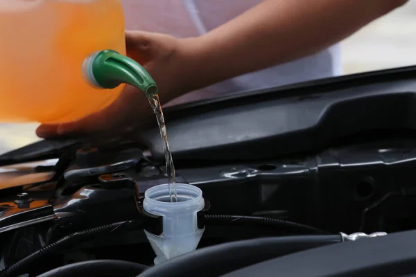 Man pouring liquid from plastic canister into car washer fluid reservoir, closeup — Stock Photo, Image