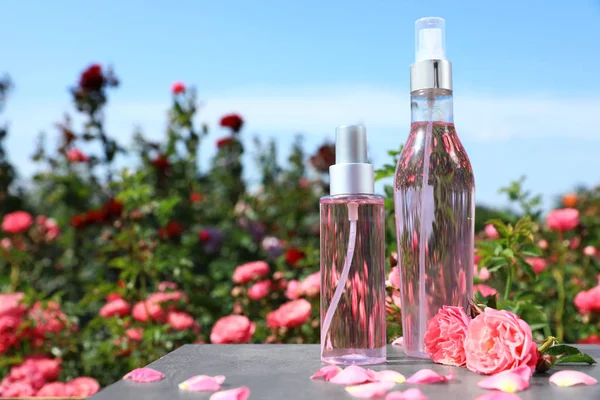 Bouteilles de toner facial à l'huile essentielle et roses fraîches sur la table sur fond flou. Espace pour le texte — Photo