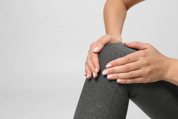 Woman having knee problems on grey background, closeup — Stock Photo, Image