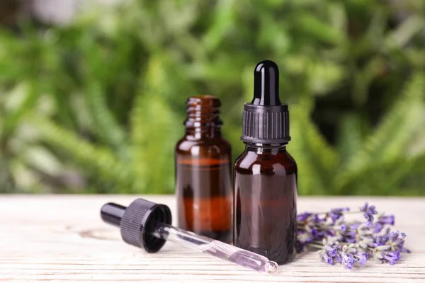 Garrafas com óleo essencial de lavanda natural sobre mesa de madeira branca contra fundo desfocado. Espaço para texto — Fotografia de Stock