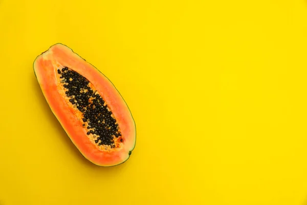 Papaya fresca y jugosa dividida en dos mitades sobre fondo amarillo, vista superior. Espacio para texto — Foto de Stock