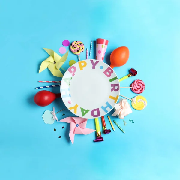 Different birthday party items and empty plate on light blue background, flat lay. Space for text