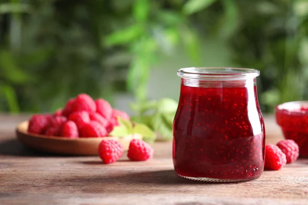 Glazen potje zoete jam met rijpe frambozen op houten tafel. Ruimte voor tekst — Stockfoto