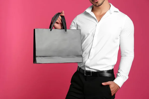 분홍색 배경에 검은 종이 가방을 들고 있는 청년, 클로즈업. 디자인 모형 — 스톡 사진