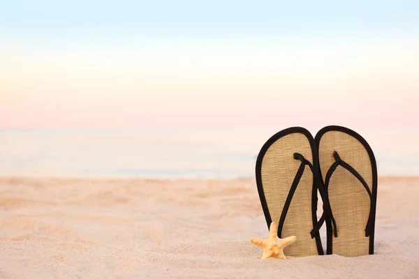 Stylish flip flops on sand near sea, space for text. Beach accessories — Stock Photo, Image