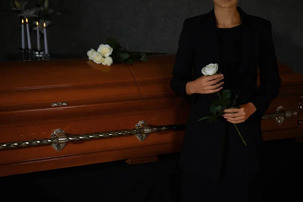Jovem com rosa branca perto do caixão na casa funerária, close-up — Fotografia de Stock