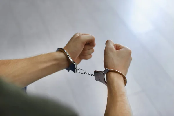 Man detained in handcuffs indoors, closeup view. Criminal law — Stock Photo, Image