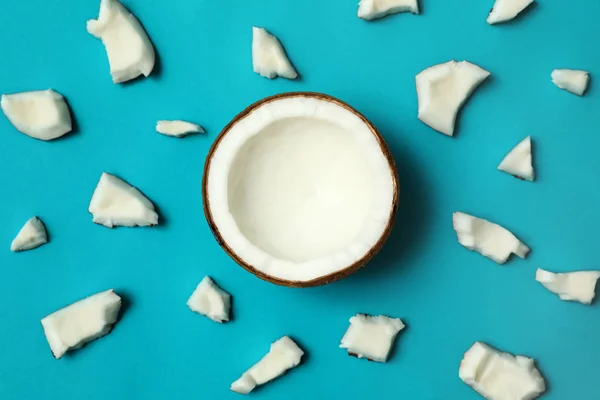 Fresh coconut pieces on blue background, flat lay