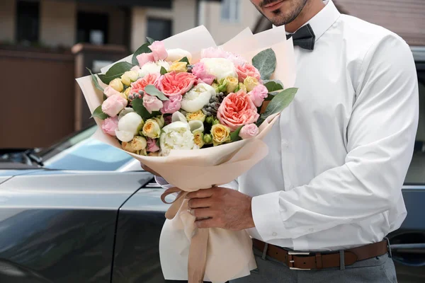 Jovem homem bonito com lindo buquê de flores perto do carro ao ar livre, vista close-up — Fotografia de Stock