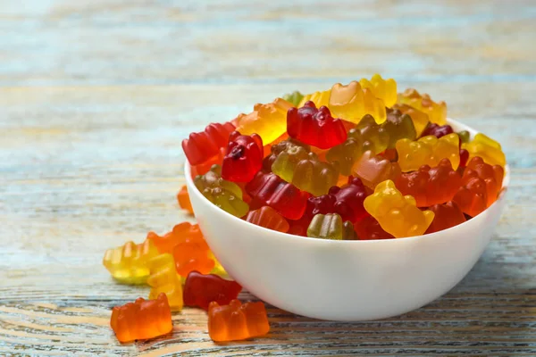 Bowl with delicious bright jelly bears on wooden table, space for text Stock Photo