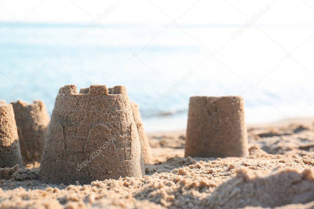 View of beach with little sand figures near sea on sunny summer day. Space for text