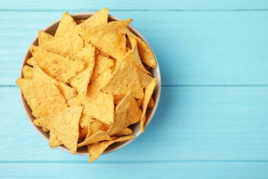Açık mavi ahşap arka planda lezzetli Meksika nachos cips kase, üst görünüm. Metin alanı