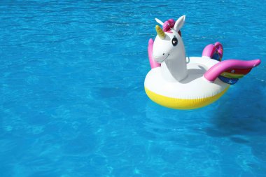 Güneşli bir gün yüzme havuzunda yüzen komik şişme Unicorn yüzük. Metin alanı
