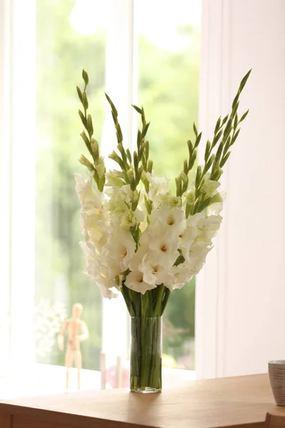 Vas med vackra vita Gladiolus blommor på träbord i rummet — Stockfoto