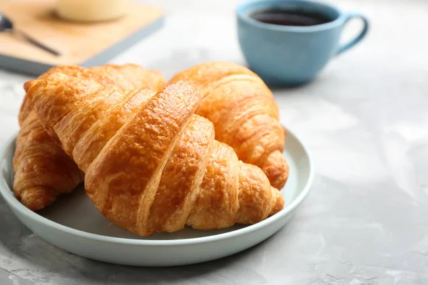 Teller mit frischen Croissants auf grauem Tisch, Nahaufnahme. französisches Gebäck — Stockfoto