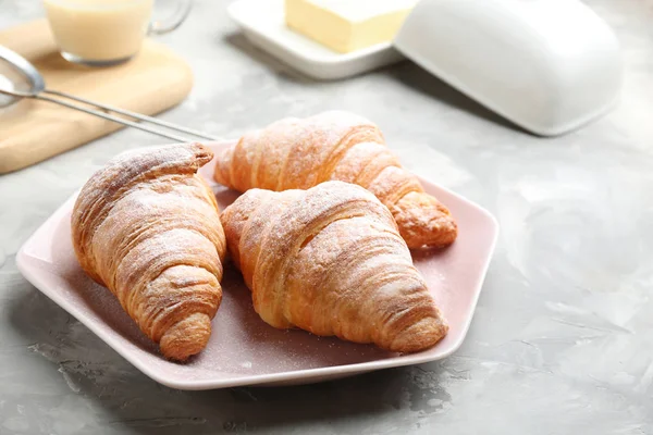 Placa de croissants frescos espolvoreada con azúcar en polvo sobre la mesa gris. Pastelería francesa — Foto de Stock