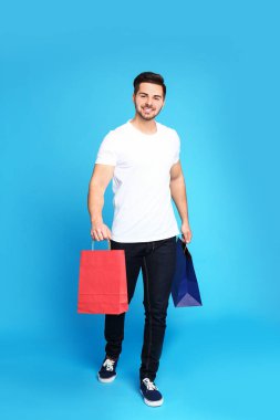 Mavi arka plan üzerinde kağıt torbalar ile genç adamın tam uzunlukta portre