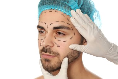 Doktor beyaz arka plan üzerinde plastik cerrahi operasyon için marker hatları ile adamın yüzünü muayene