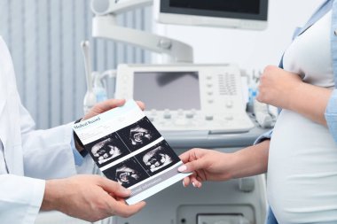 Doktor klinikte gelecekteki anneye bebeğin ultrason görüntüleri gösteren, closeup
