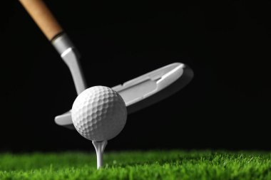 Siyah arka plan, metin alanı karşı yapay çim üzerinde kulüp ile golf topu vurmak
