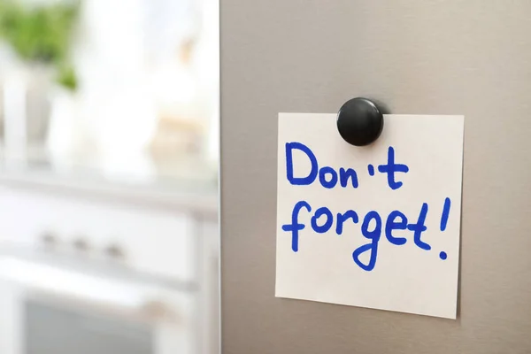 Uwaga z tekstem "nie zapomnij" i magnes na drzwiach lodówki w kuchni. Miejsce na tekst — Zdjęcie stockowe