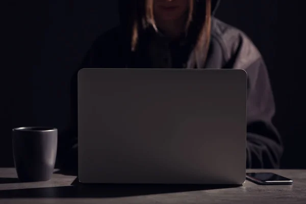 Женщина с ноутбуком и смартфоном за столом в темноте, крупным планом — стоковое фото