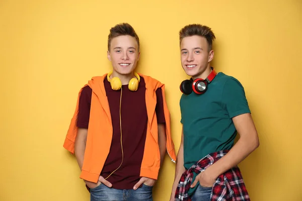 Teenager-Zwillingsbrüder mit Kopfhörern auf farbigem Hintergrund — Stockfoto
