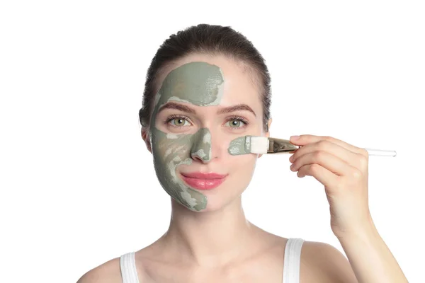 Fiatal nő alkalmazó agyag maszkot az arcán a fehér háttér előtt. Bőrápolás — Stock Fotó