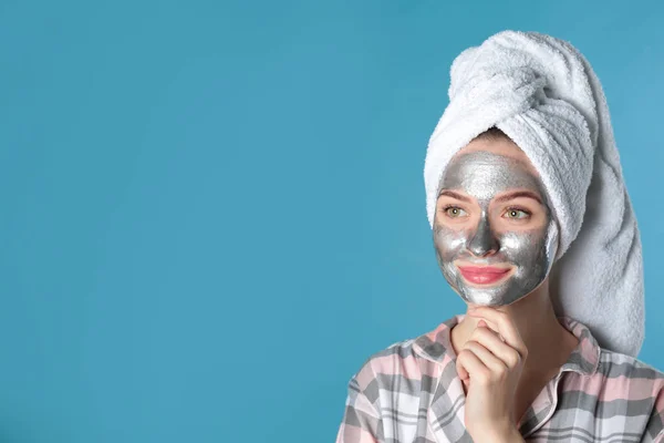 Wanita muda dengan topeng pembersih di wajahnya terhadap latar belakang warna, ruang untuk teks. Perawatan kulit — Stok Foto