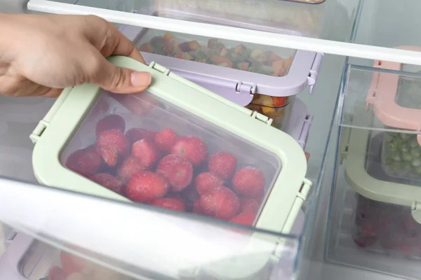 Wanita mengambil kotak dengan strawberry beku dari kulkas, closeup — Stok Foto