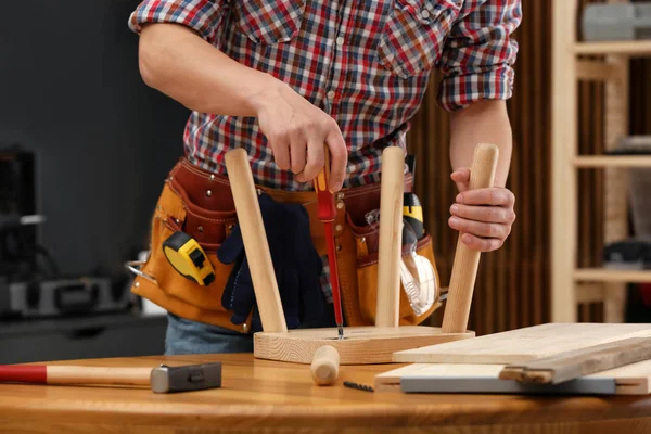 Młody człowiek pracujący naprawy drewniany stołek za pomocą śrubokręt w pomieszczeniu, zbliżenie — Zdjęcie stockowe