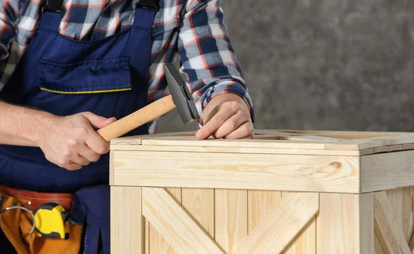 Pracujący mężczyzna młotkiem w drewnianej skrzyni w pomieszczeniu, zbliżenie — Zdjęcie stockowe