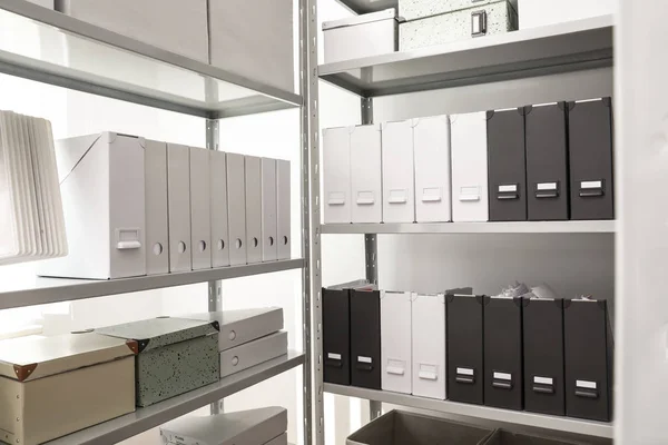 Folders and boxes with documents on shelves in archive