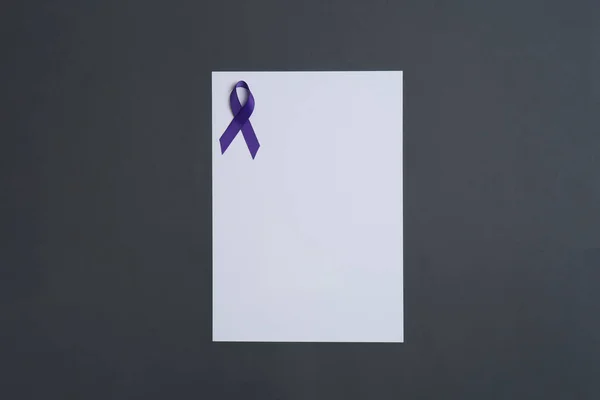 Purple awareness ribbon and blank card on black background, top view with space for text