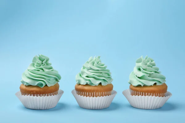 Ízletes Cupcakes krémmel világoskék háttér — Stock Fotó