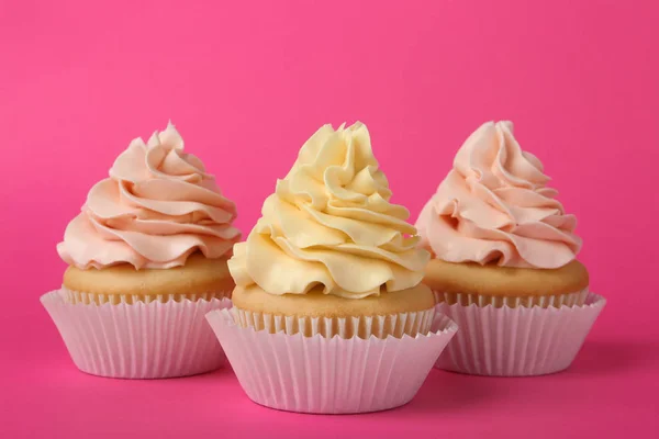 Smakelijke cupcakes met crème op roze achtergrond — Stockfoto