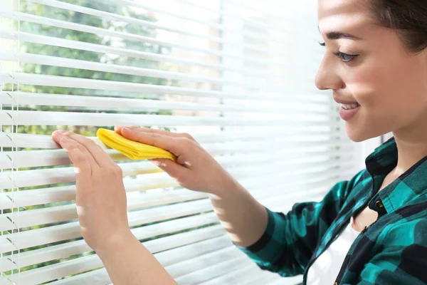 Mooie vrouw schoonmaken raam jaloezieën met Rag binnenshuis, close-up — Stockfoto