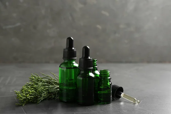 Samenstelling met flessen Conifer etherische olie op grijze tafel — Stockfoto