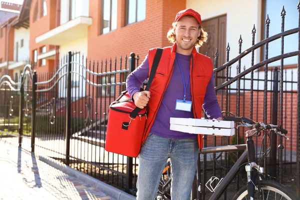 Courrier masculin livrant de la nourriture en ville le jour ensoleillé — Photo