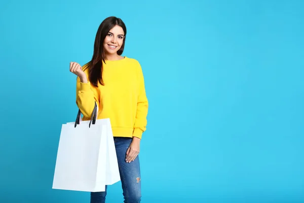 Ritratto di giovane donna con sacchetti di carta su sfondo blu. Spazio per testo — Foto Stock