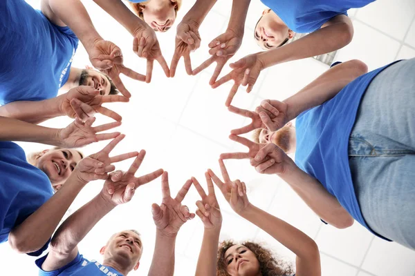 Equipo de voluntarios poniendo sus manos juntas sobre fondo claro, vista inferior — Foto de Stock