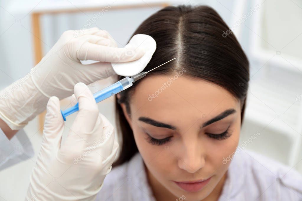 Young woman with hair loss problem receiving injection in salon