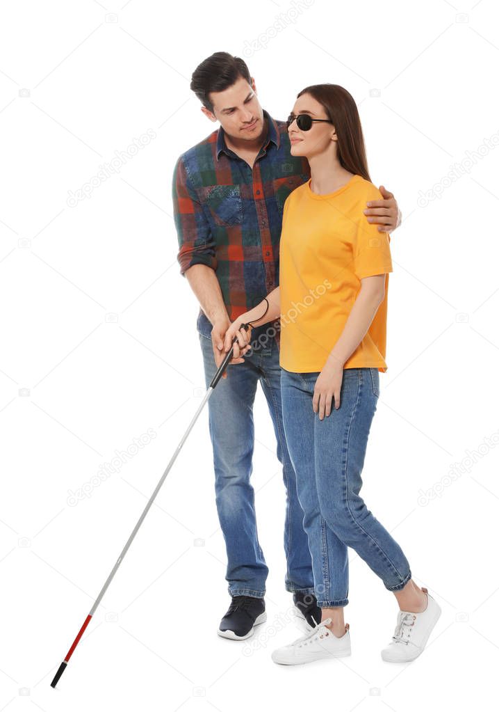 Man assisting blind woman with long cane on white background