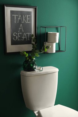 Dekor elemanları, kağıt rulo ve yeşil duvara yakın tuvalet kabı. Banyo iç