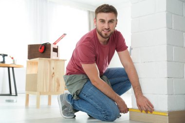 Evde ölçüm bandı kullanarak genç çalışan adam, metin için boşluk